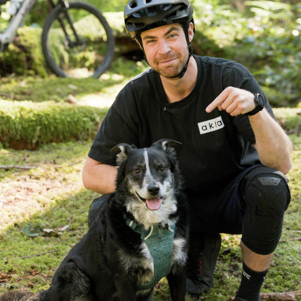 Jason Lucas kneeling beside his dog Maya in the forest